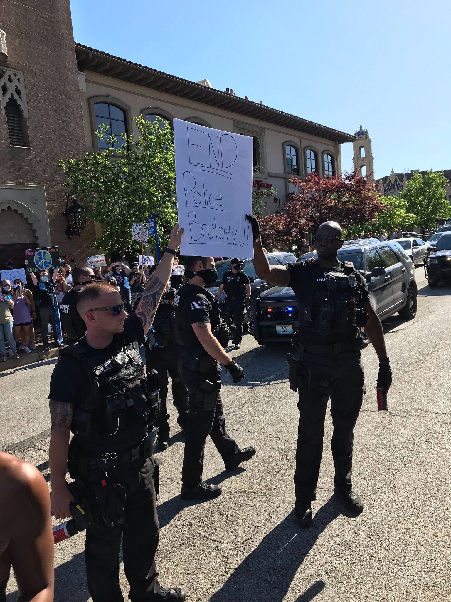 Police hold a sign that reads "End police brutality"