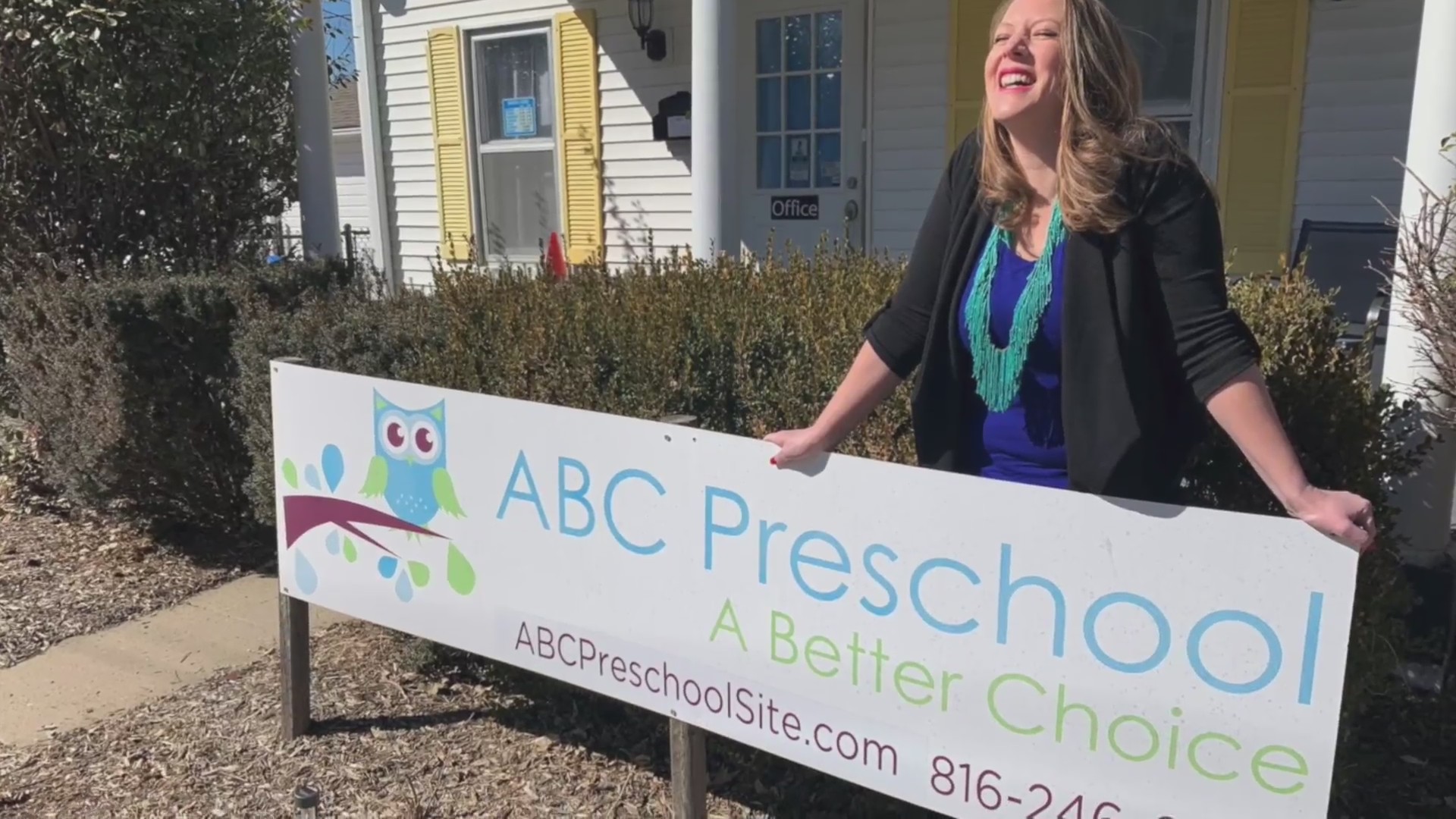 Picture of woman standing behind new preschool sign